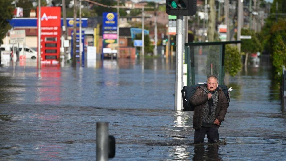 A man walks on a flooded street in Melbourne