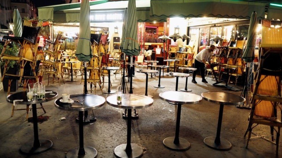 A staff member prepares to close a restaurant minutes before the late-night curfew in Paris