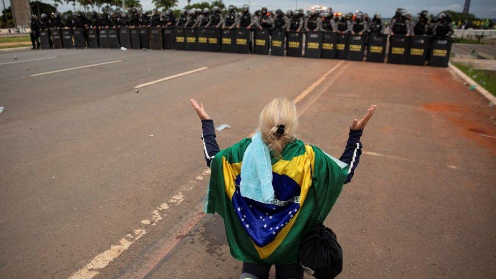 A supporter of Brazil's far-right former President Jair Bolsonaro prays in front of police officers during protests in Brasilia,