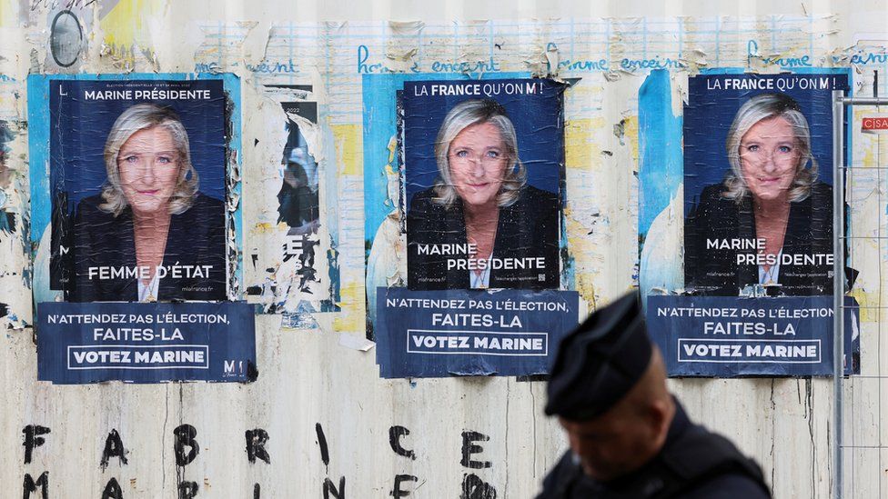 Three campaign posters for Marine Le Pen are seen on a wall, none using her second name