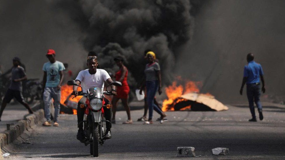 A man drives past a burning barricade during a protest against Prime Minister Ariel Henry's government and insecurity, in Port-au-Prince, Haiti March 1, 2024