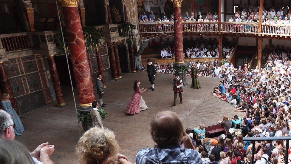Audience members watch a production of A Midsummer Night's Dream at Shakespeare's Globe theatre