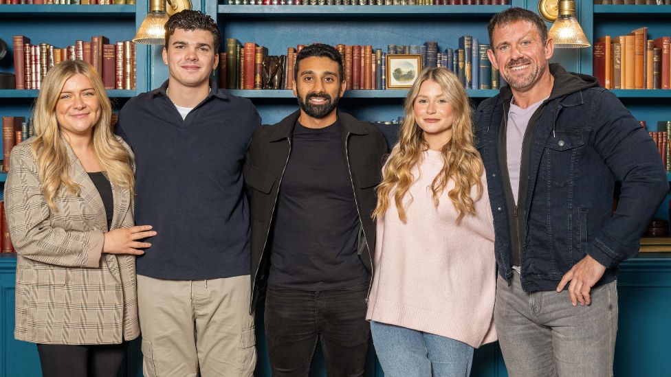 The Traitors contestants Evie Morrison, Harry Clark, Jaz Singh, Mollie Pearce and Andrew Jenkins standing in front of a bookcase