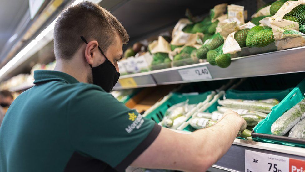 Morrisons staff shelving vegetables