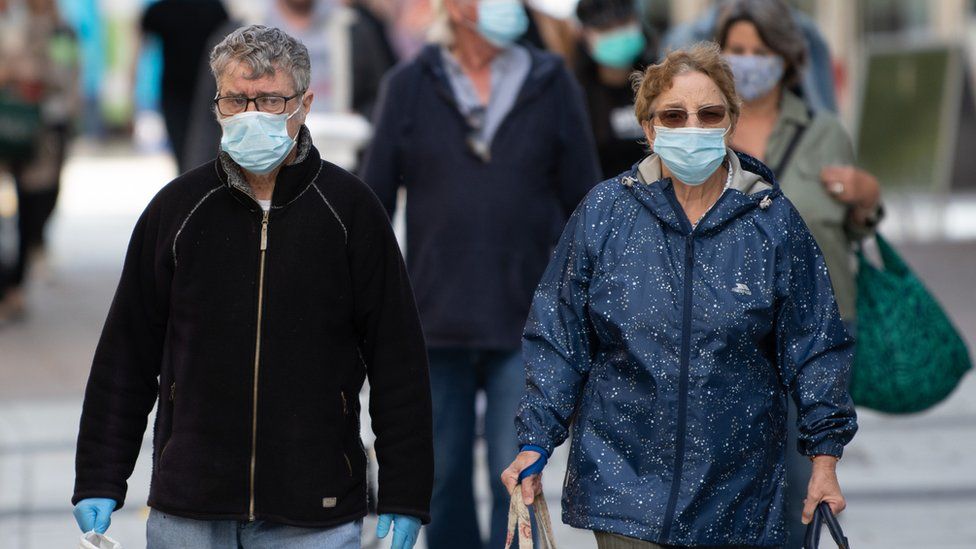 A man and woman wear surgical face masks on Queen Street on September 23, 2020 in Cardiff, Wales