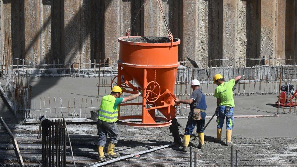 Construction workers pour concrete for residential buildings under construction at a large construction site in Munich, southern Germany, May 11, 2022