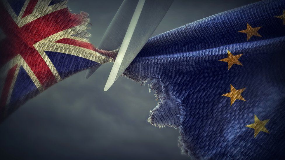 A pair of scissors cutting fabric showing the Union Jack and the EU flag