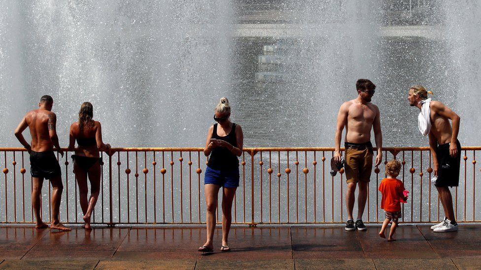 People cool off at a fountain in Battersea Park
