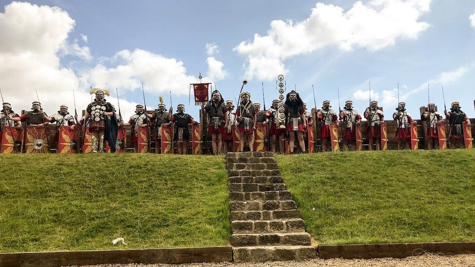 Men in Roman military costumes stand in a line