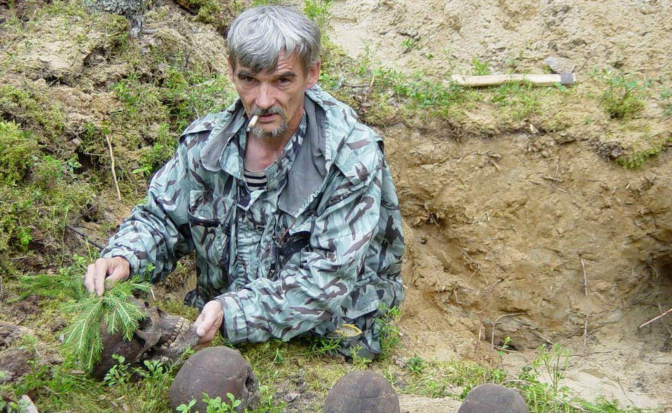 Yuri Dmitriyev with victims' skulls at mass grave