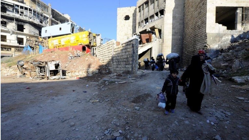 People, who evacuated the eastern districts of Aleppo, carry their belongings as they walk in a government held area of Aleppo on 9 December 2016.