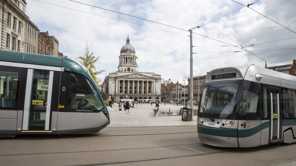 Two trams pass each other in front of the central square in front of Nottingham's town hall