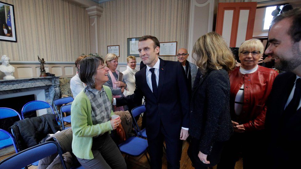 French President Emmanuel Macron (C) arrives to attend the city council at the town hall in Gasny before the launching of the Grand Debate designed to find ways to calm yellow vest protests in France, on January 15, 2019