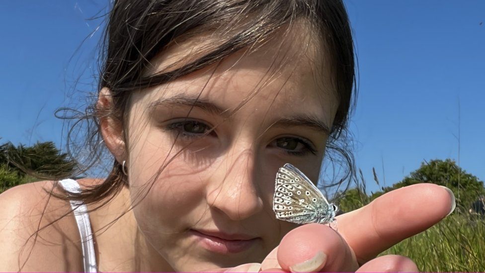 Girl holds a butterfly on her finger as part of a survey