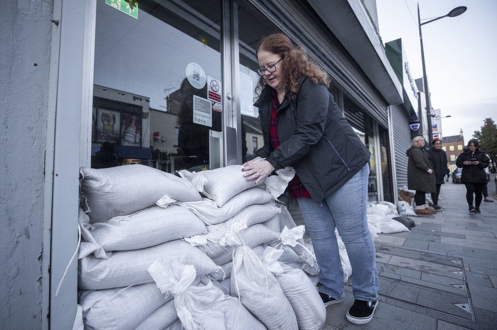 A woman stacks sandbags outside a shop in Downpatrick