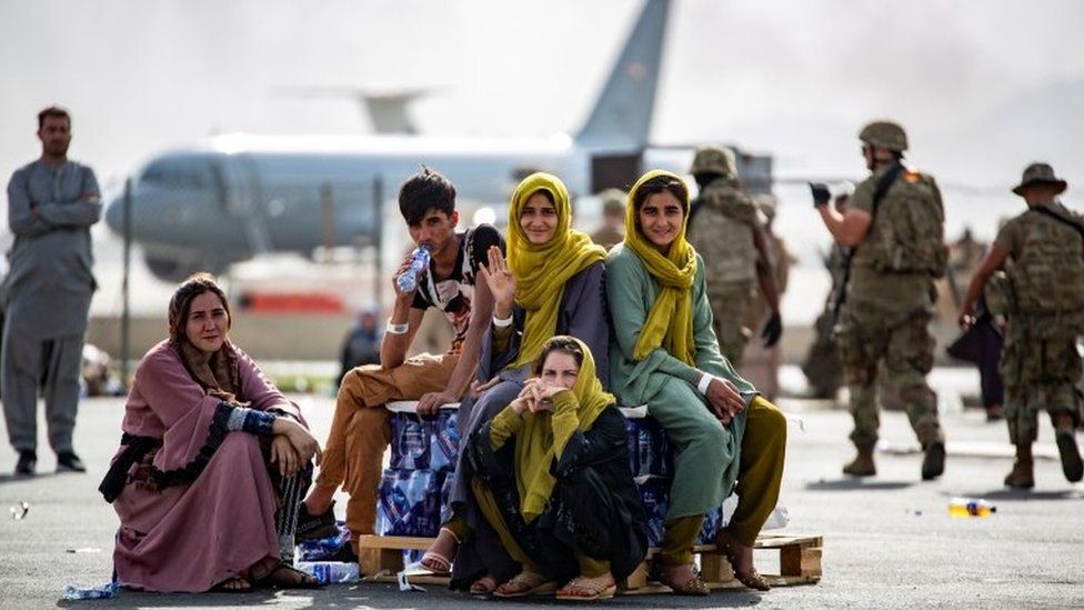 Afghans wave as they wait to board evacuation flights in Kabul