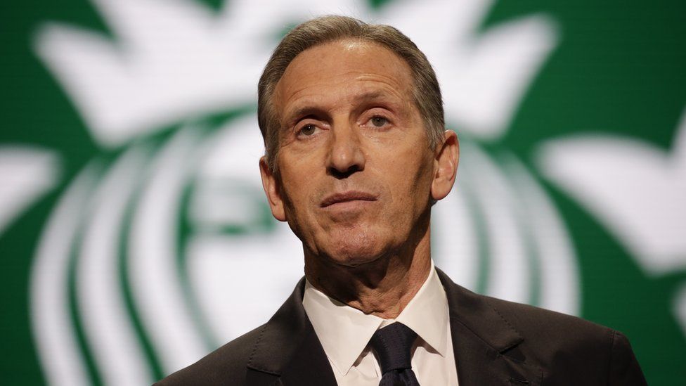 Mr Schultz in front of Starbucks logo