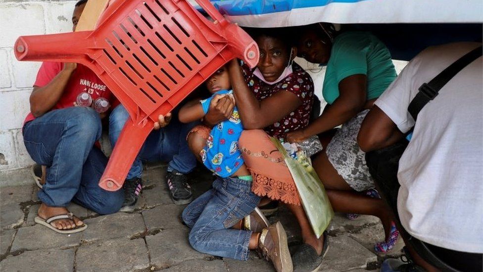 Migrants use a chair to protect themselves from rocks during a protest by migrants to demand speedy processing of humanitarian visas to continue on their way to the United States, outside the office of the National Migration Institute (INM) in Tapachula, Mexico February 22, 2022.