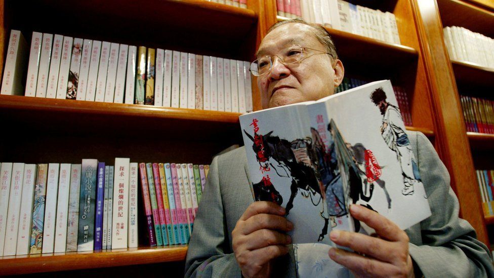 Louis Cha holds his book "Book and Sword, Gratitude and Revenge" at his office in Hong Kong, 2002