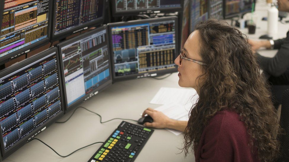 Female trader looking at screens - stock image