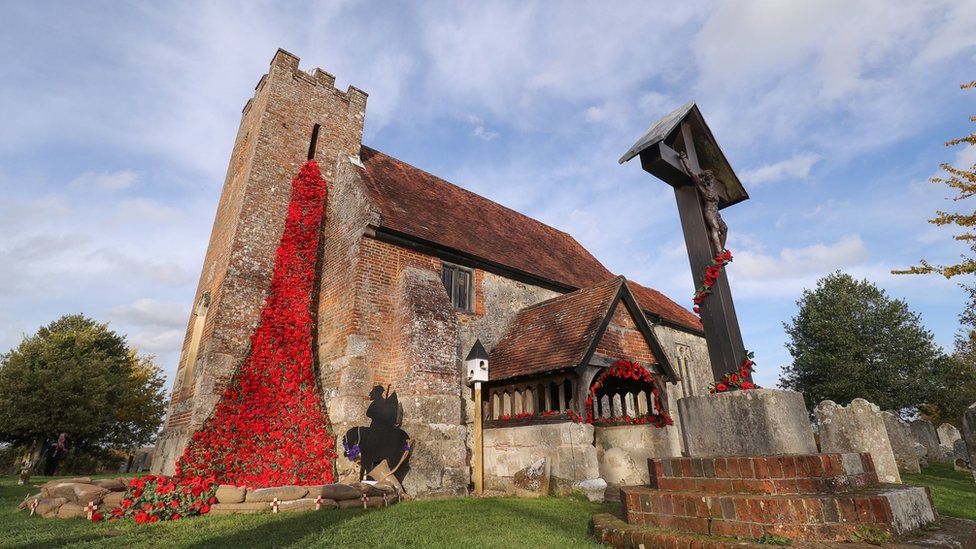 Over 4000 individually knitted poppies, part of a piece of art called "Over the Top", cascade from the tower at St John the Baptist church in North Baddesley, Hampshire