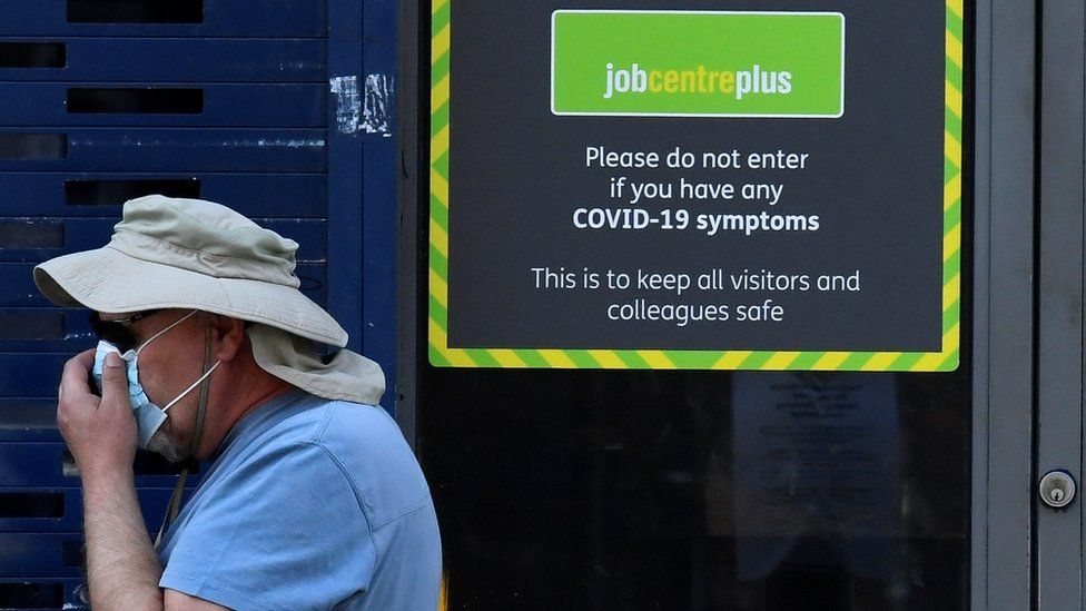 A person wearing a protective face mask walks past a Job Centre Plus office, amidst the outbreak of the coronavirus disease