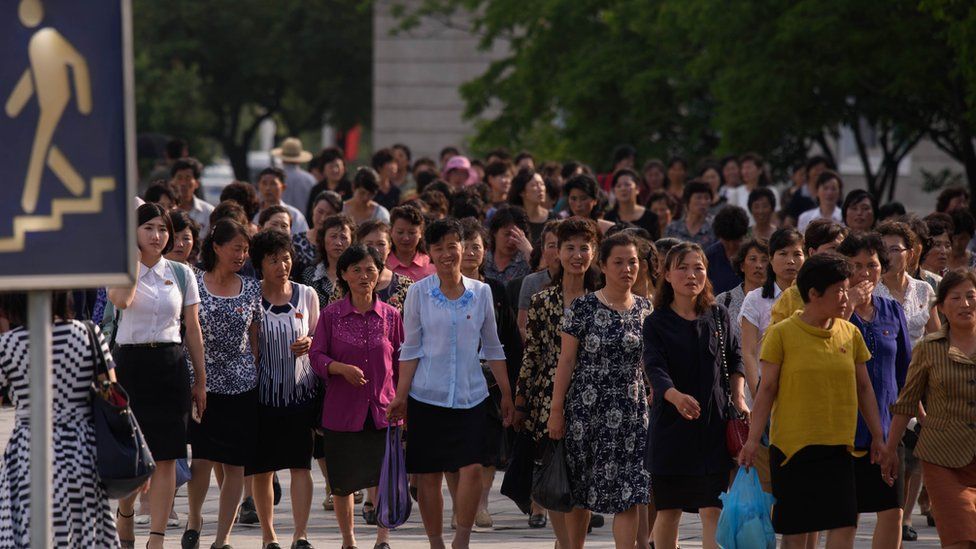A group of women walk along a street in Pyongyang as Chinese President Xi Jinping begins a historic visit to Pyongyang