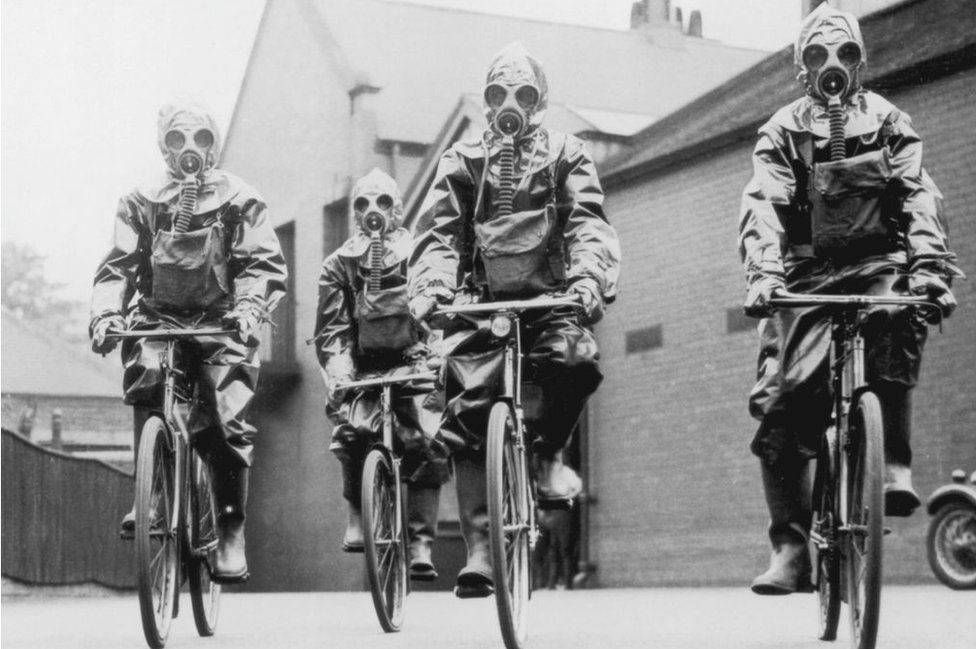 Cyclists of the London police unit wearing gas masks and protective suits during an exercise, 1936. (