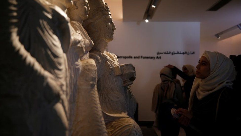 Women examine sculptures during museum reopening