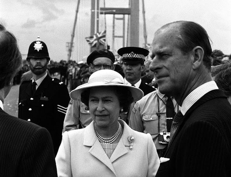 The Queen and Prince Philip with a crowd of people on the bridge