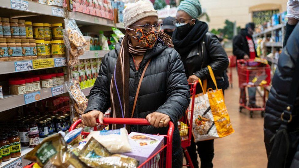 Женщина делает покупки в супермаркете США в маске.