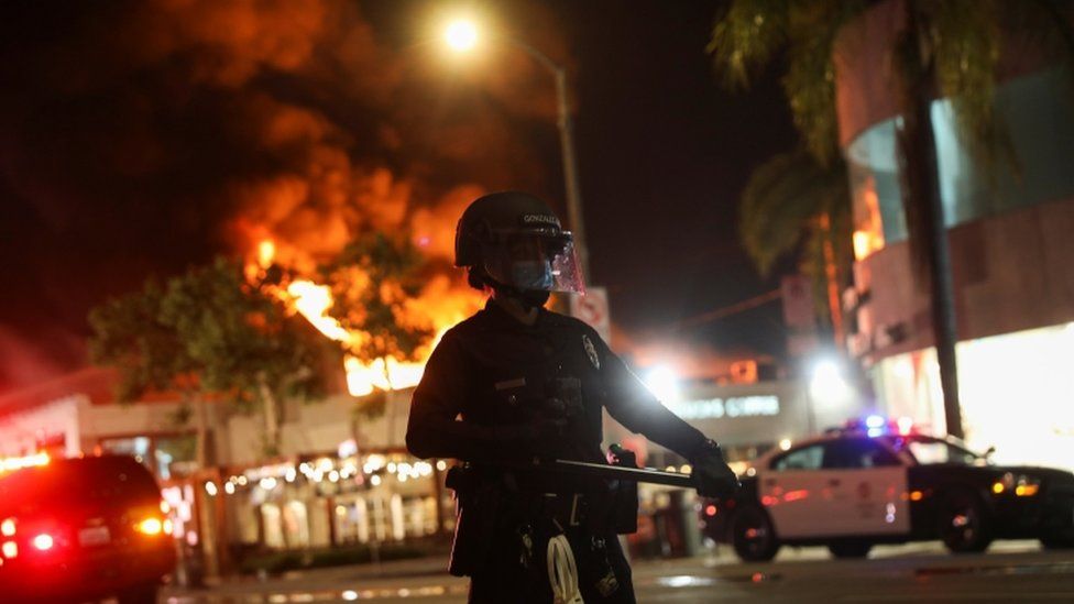 Police are deployed as a fire burns in Los Angeles, which is under curfew