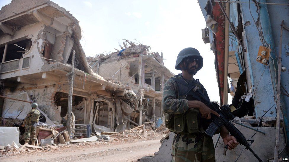 Pakistani soldiers stand guard at a destroyed empty bazaar during a military operation against Taliban militants in the main town of Miranshah in North Waziristan on 9 July 2014