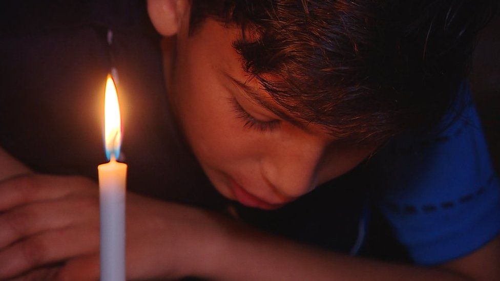 Boy reads by candlelight in an apartment in Gaza City