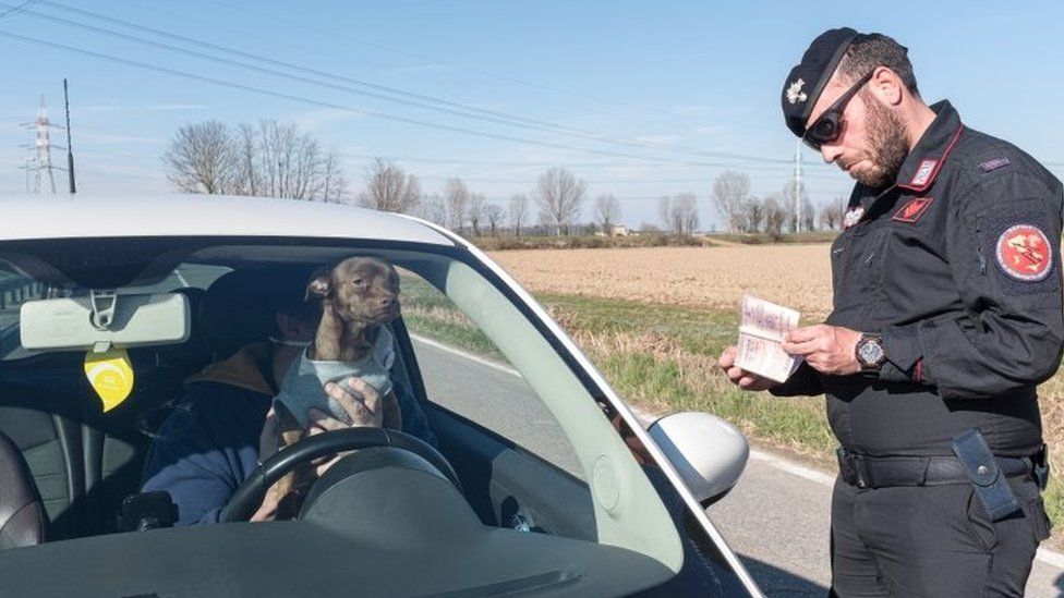 A police officer checks documents of a man in a car at a checkpoint in San Fiorano, Italy. Photo: 8 March 2020