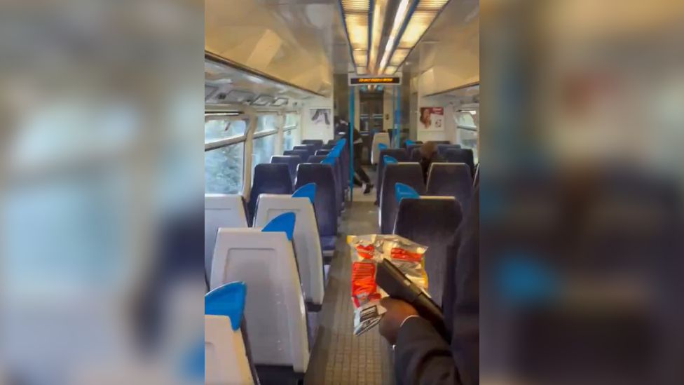 An image from a video on social media shows the attacker bending down over the victim, as passengers gather at the other end of the carriage