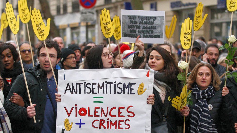 Demonstrators hold signs against anti-Semitism during a silent march in Paris on March 28, 2018, in memory of Mireille Knoll, an 85-year-old Jewish woman murdered in her home in what police believe was an anti-Semitic attack.