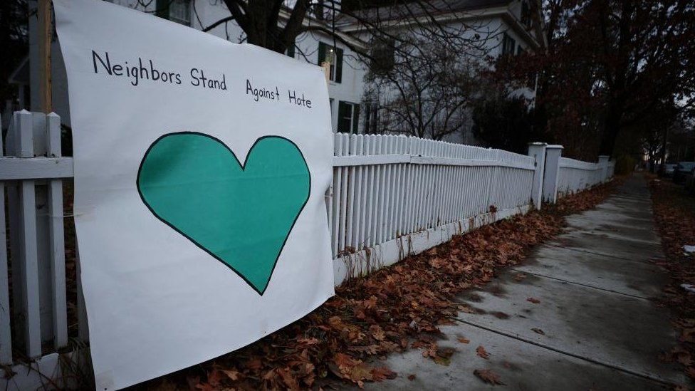 A sign reading "Neighbors stand against hate" stands outside the Burlington Friends Meeting house on the same street where three college students of Palestinian descent were shot over the weekend, in Burlington, Vermont