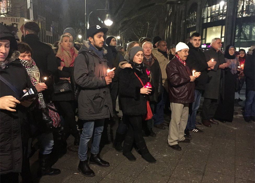 People hold candles close to the scene where a truck ploughed into a crowded Christmas market outside the Kaiser Wilhelm Memorial Church in Berlin, 20 December