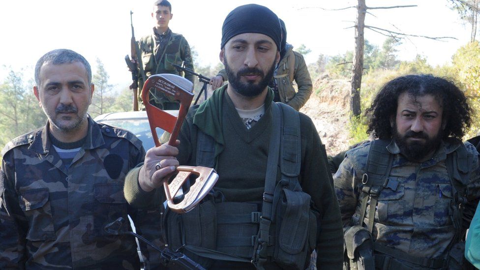 Alpaslan Celik, a deputy commander in a Syrian Turkmen rebel brigade, holds handles believed to be parts of a parachute of the downed Russian warplane (24 November 2015)