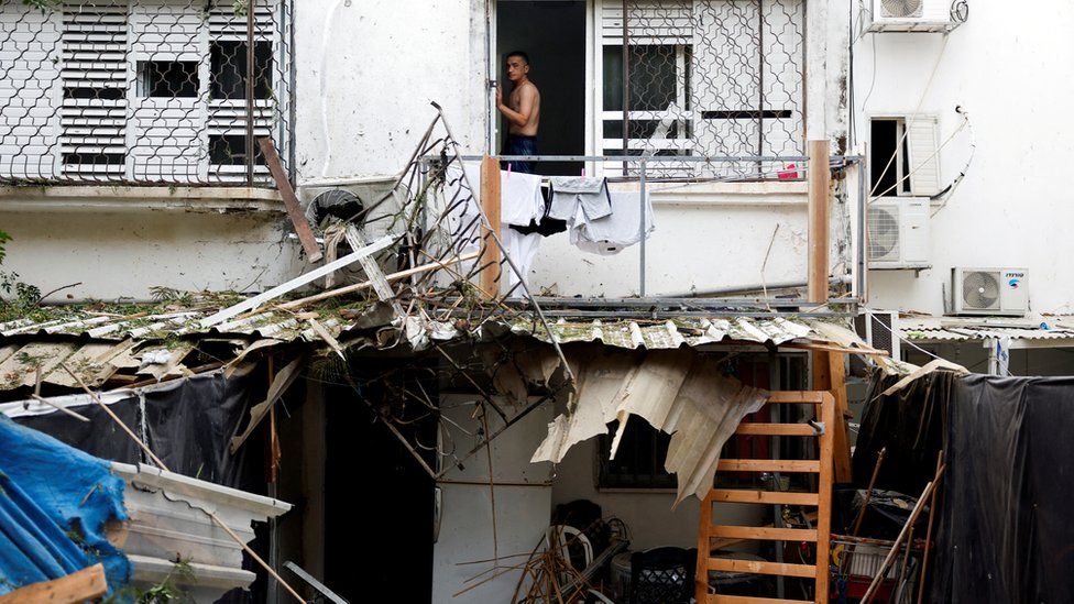 A man looks out from a window of a building in the Israeli city of Askhelon that was by a rocket fired from Gaza (9 October 2023)