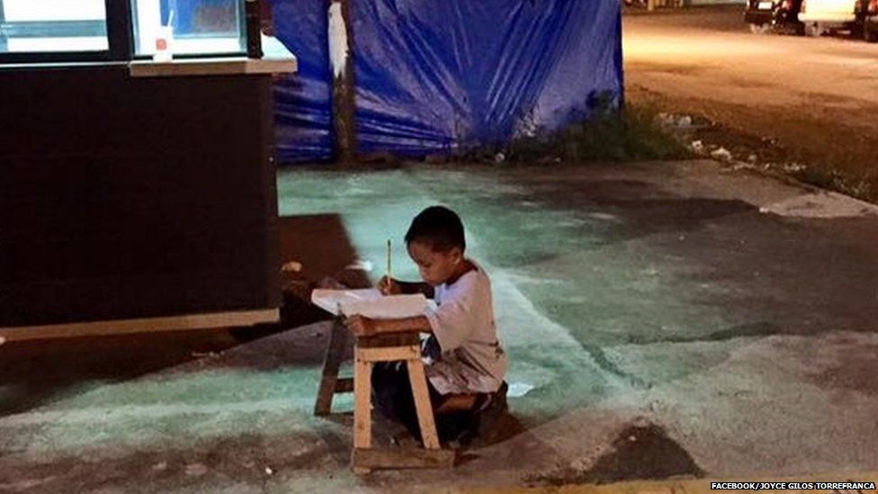 boy doing homework under street light