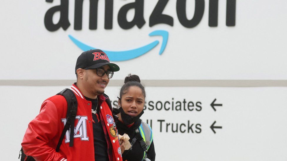 workers in front of Amazon sign