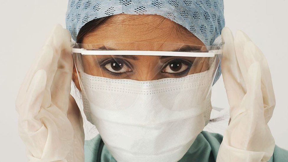 Close up of female UK NHS EMS doctor's face,wearing blue PPE