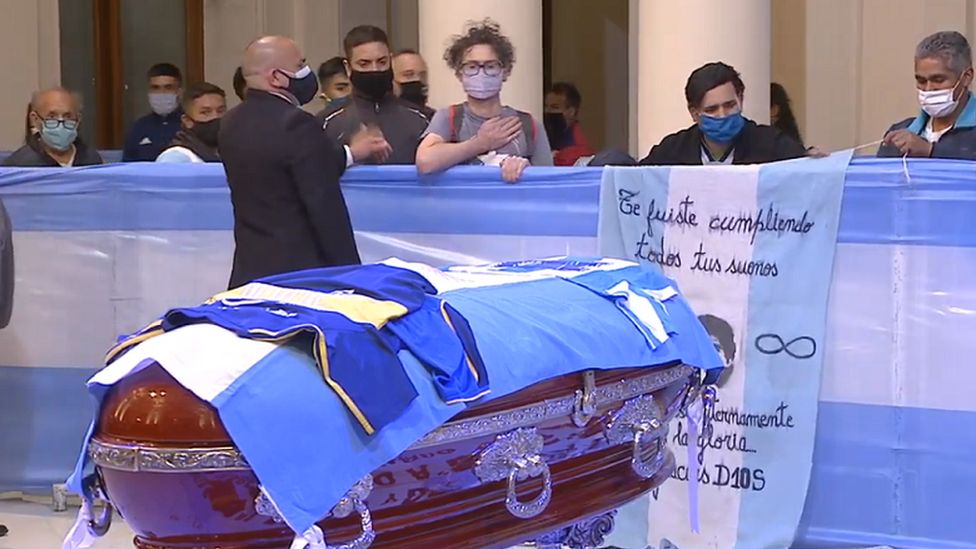 Fans walks past Maradona's coffin