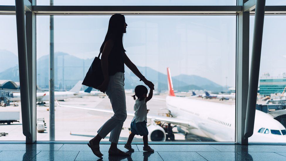 A silhouette of a woman and a child walking past a plane