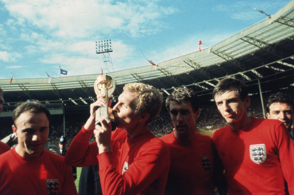 England captain Bobby Moore kissing the Jules Rimet trophy as the team celebrate winning the 1966 World Cup final