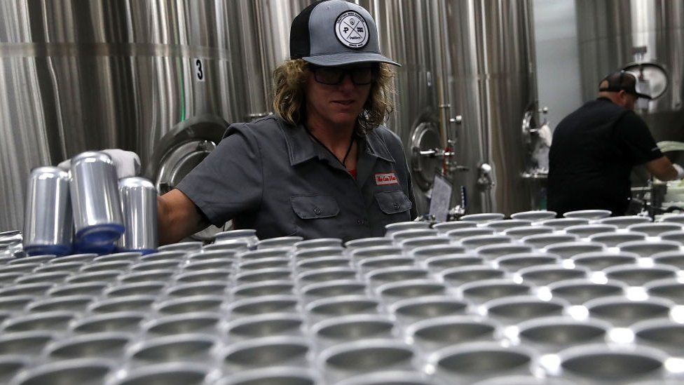 Kathryn Fisher with Can Van, a mobile canning company, places empty aluminum cans on a conveyor belt to be filled with beer at Devil's Canyon Brewery on June 6, 2018 i