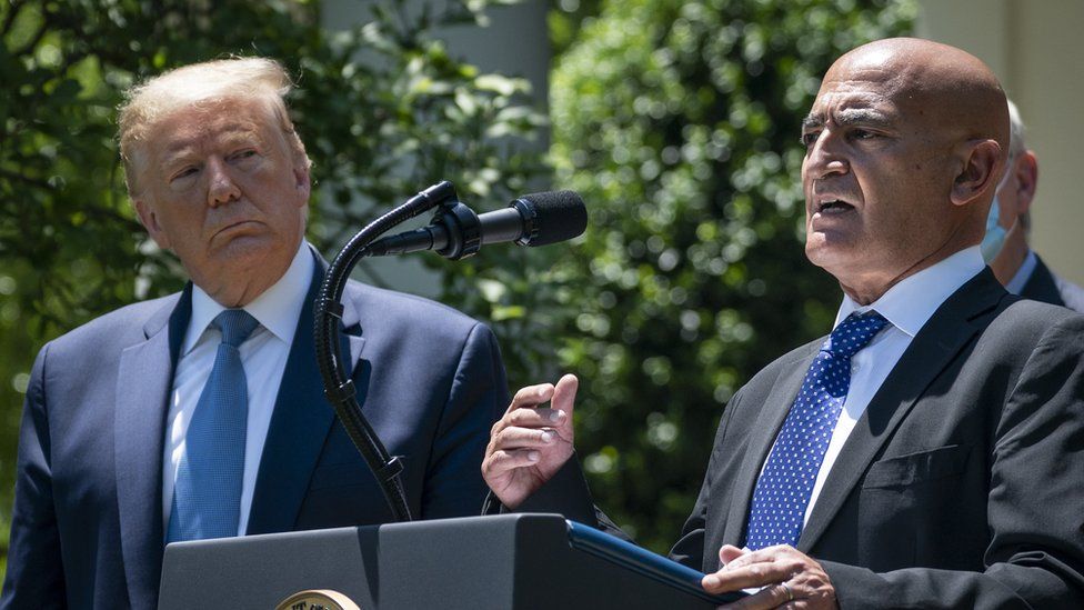President Donald Trump listens as Moncef Slaoui, the former head of GlaxoSmithKlines vaccines division, speaks about coronavirus vaccine development in the Rose Garden of the White House in May 2020 in Washington