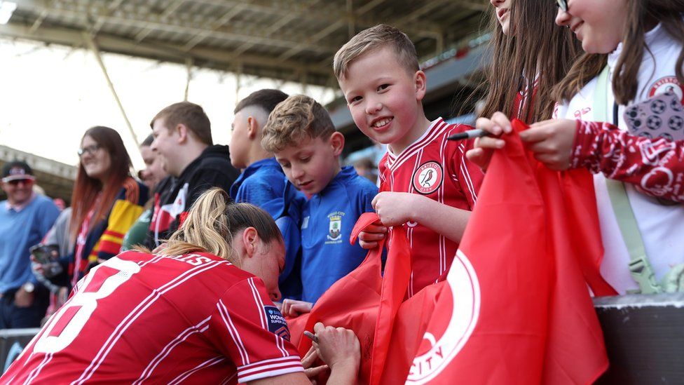 A Bristol City Women's player signs autographs for young fans at Ashton Gate after the game with Liverpool